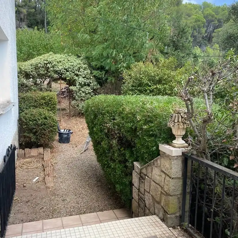 Haie taillée au carré le long d'une allée de gravier, en bas d'un escalier carrelé, à Saint-Maximin